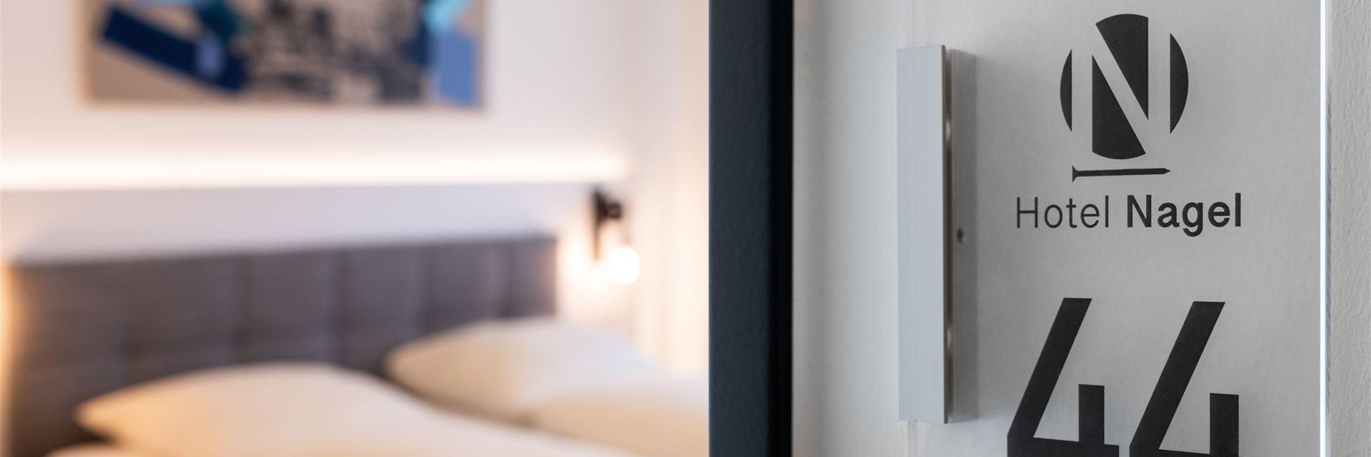 Nahaufnahme einer Zimmernummer mit im Hintergrund das Zimmer (unscharf)